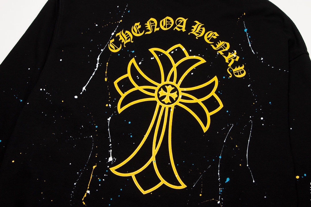 Sweat-shirt noir à motif de cœurs chromés, coulures de peinture et croix jaune.
